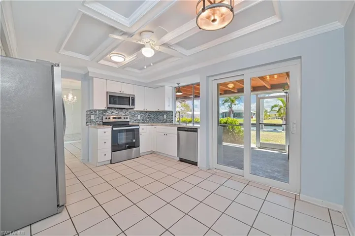 Kitchen featuring coffered ceiling, tasteful backsplash, appliances with stainless steel finishes, white cabinets, and light countertops