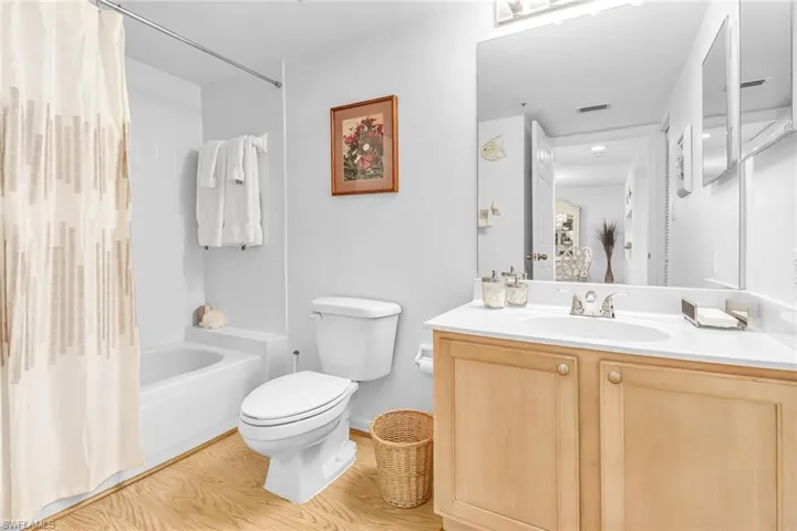 Full bathroom with vanity, shower / tub combo with curtain, toilet, and hardwood / wood-style floors