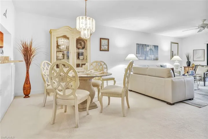 Carpeted dining space featuring ceiling fan with notable chandelier