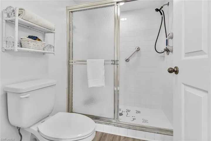 Bathroom featuring toilet, a shower with shower door, and hardwood / wood-style floors