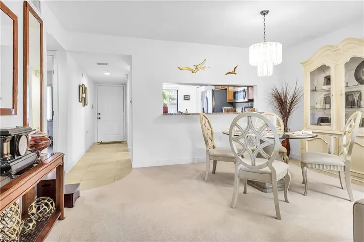 Dining area with light colored carpet and an inviting chandelier
