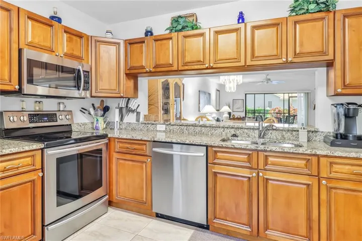 Kitchen featuring sink, light stone counters, and stainless steel appliances