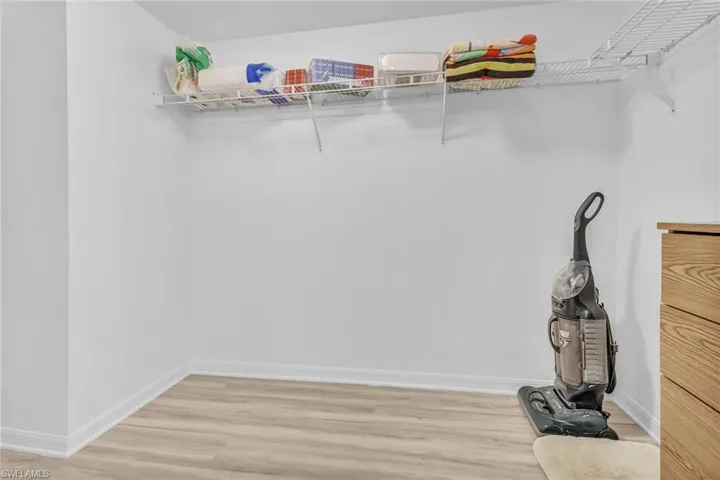 Walk in closet with light hardwood / wood-style floors