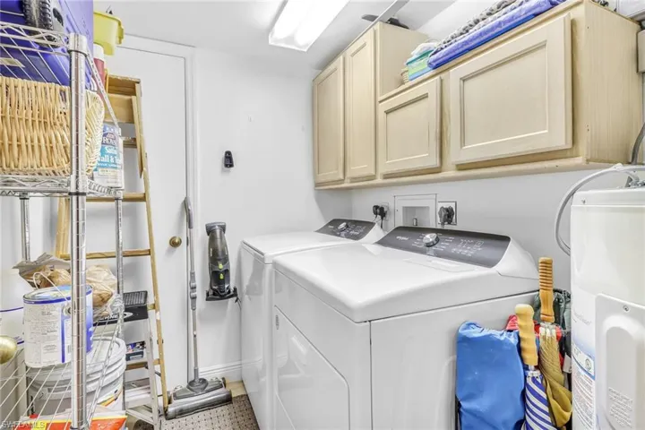 Laundry area with tile patterned floors, cabinets, washer and dryer, and electric water heater