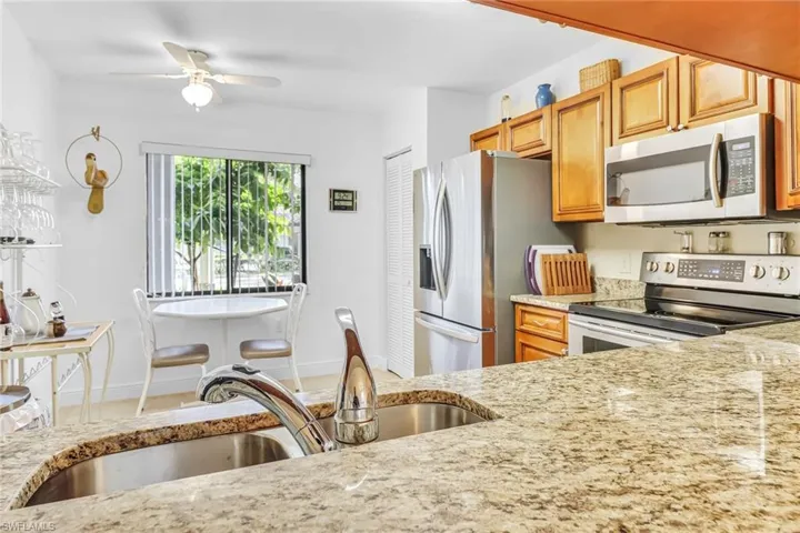 Kitchen with stainless steel appliances, light stone countertops, and ceiling fan