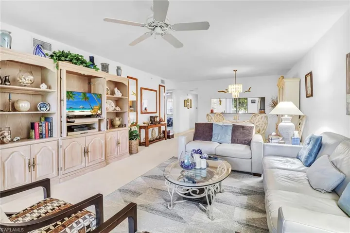Carpeted living room featuring ceiling fan with notable chandelier