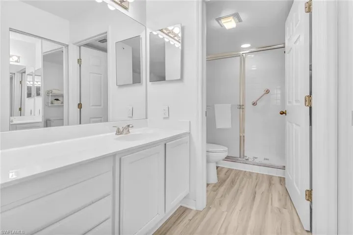 Bathroom featuring hardwood / wood-style floors, vanity, a shower with shower door, and toilet