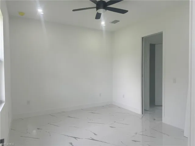 Empty room featuring ceiling fan and light tile patterned floors