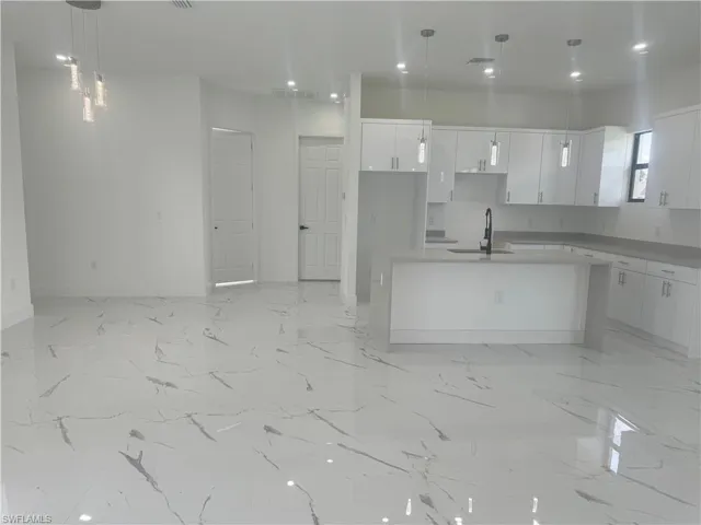 Kitchen with sink, pendant lighting, white cabinets, and light tile patterned floors