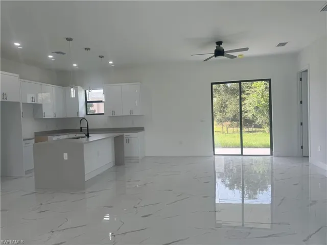 Kitchen with plenty of natural light, white cabinets, and light tile patterned floors