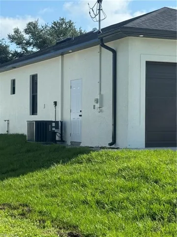Rear view of house featuring central AC unit and a yard