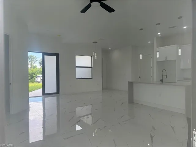 Unfurnished living room featuring light tile patterned flooring, sink, and ceiling fan