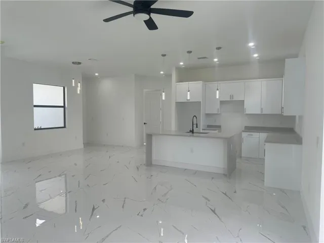 Kitchen with a center island with sink, light tile patterned flooring, and hanging light fixtures