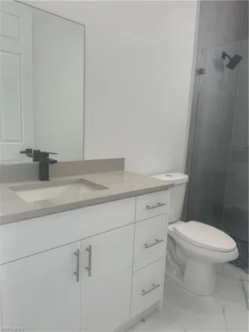 Bathroom with tile patterned flooring, an enclosed shower, toilet, and vanity