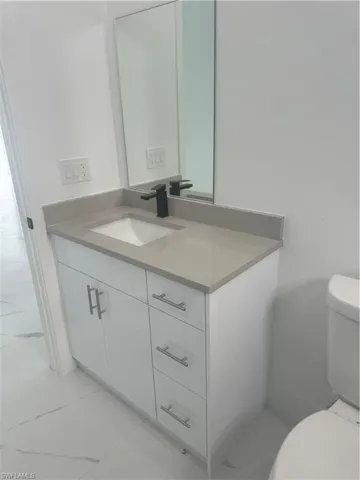 Bathroom featuring tile patterned flooring, toilet, and vanity