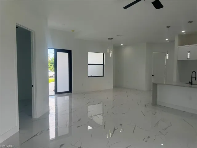 Unfurnished living room featuring light tile patterned floors, sink, and ceiling fan