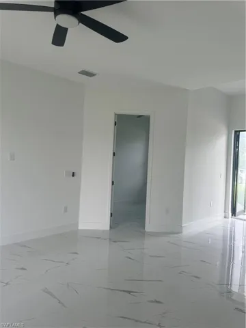 Tiled spare room featuring ceiling fan