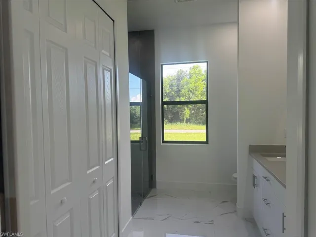 Bathroom with tile patterned floors, toilet, vanity, and a healthy amount of sunlight