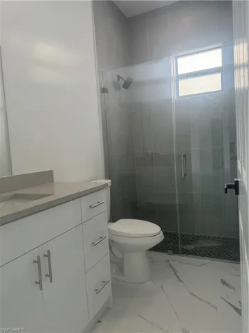 Bathroom featuring tile patterned flooring, an enclosed shower, toilet, and vanity