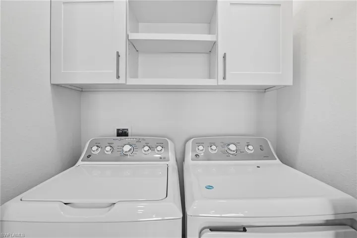 Laundry room with a textured wall, cabinet space, and separate washer and dryer