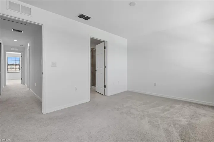 Empty room featuring light colored carpet and baseboards