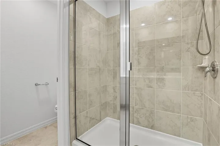 Full bath with a shower stall and baseboards