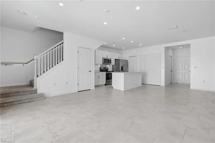Unfurnished living room featuring recessed lighting and stairway