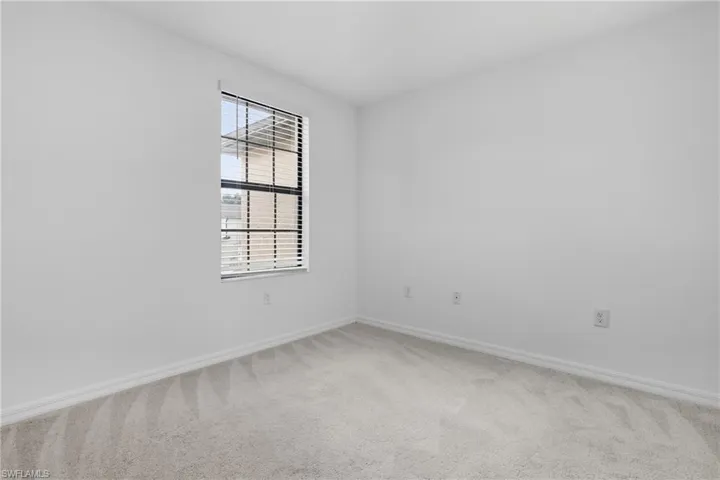 Unfurnished room with baseboards and light carpet