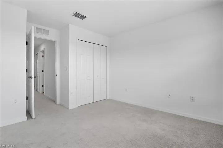 Unfurnished bedroom with light carpet and a closet