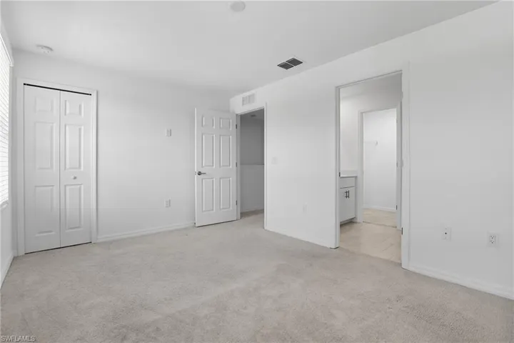 Unfurnished bedroom with light carpet, a closet, and ensuite bathroom