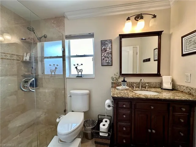 Main Bathroom featuring vanity, toilet, crown molding, and walk in shower