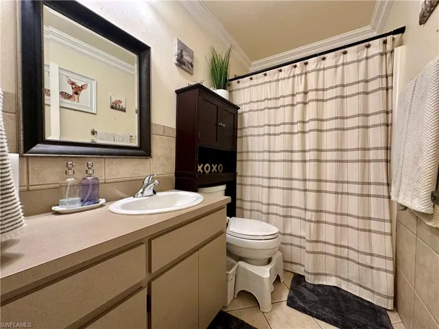 Guest Bathroom with vanity, ornamental molding, toilet, tile patterned flooring, and backsplash