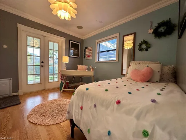 Guest Bedroom or Den, Bedroom with ornamental molding, access to outside, wood-type flooring, and french doors and custom build cabinet closets