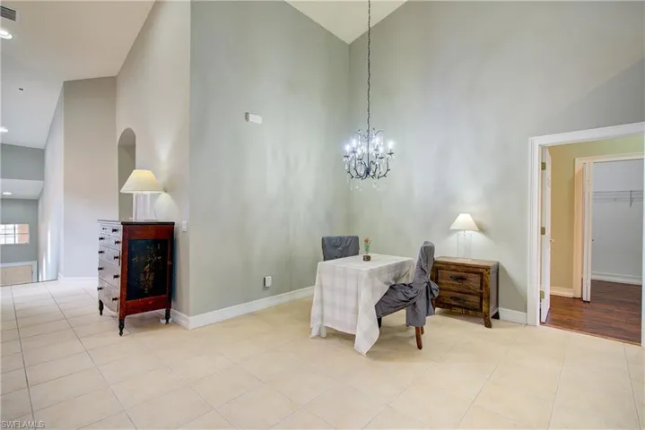 Tiled office space featuring an inviting chandelier and high vaulted ceiling