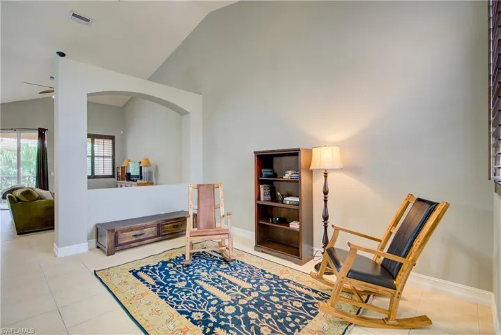Living area featuring lofted ceiling, light tile patterned floors, and ceiling fan
