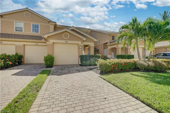 View of property with decorative driveway, a garage, a front lawn, and stucco siding