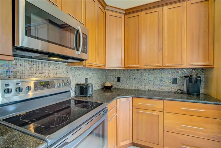 Kitchen featuring tasteful backsplash, stainless steel appliances, and dark stone counters