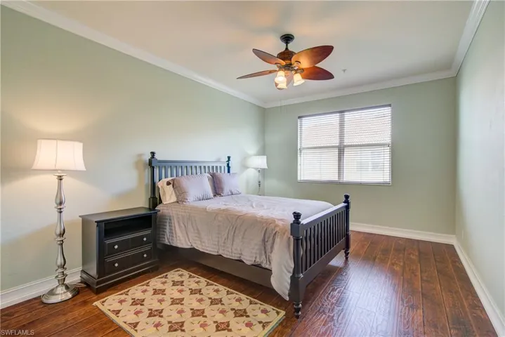 Bedroom with ornamental molding, dark hardwood / wood-style flooring, and ceiling fan