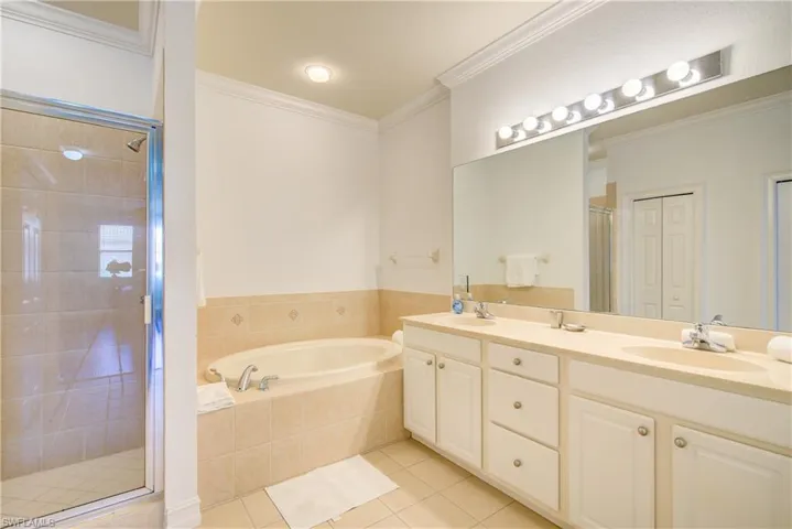 Bathroom featuring independent shower and bath, crown molding, tile patterned floors, and vanity