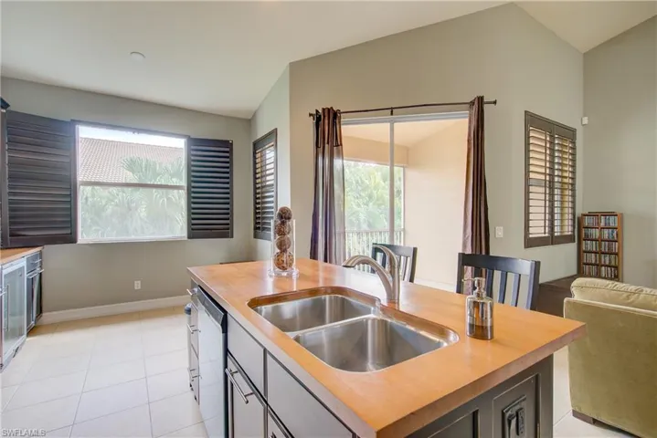 Kitchen with vaulted ceiling, a wealth of natural light, an island with sink, sink, and stainless steel dishwasher
