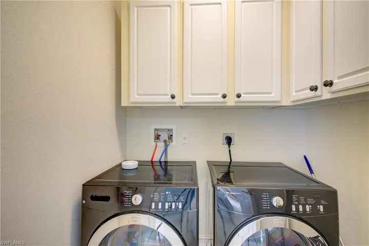 Clothes washing area featuring independent washer and dryer and cabinets