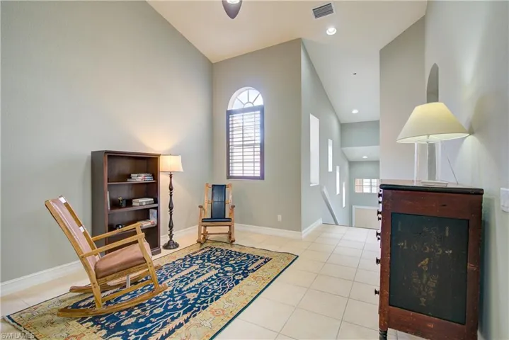 Sitting room with light tile patterned floors and high vaulted ceiling