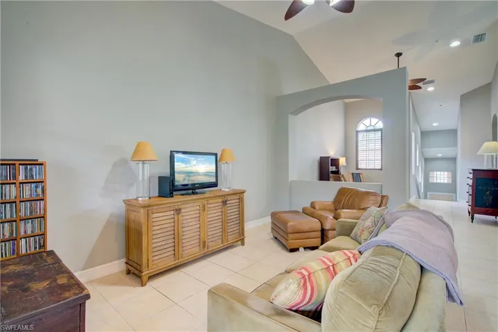 Living room featuring ceiling fan, lofted ceiling, a fireplace, and light tile patterned floors