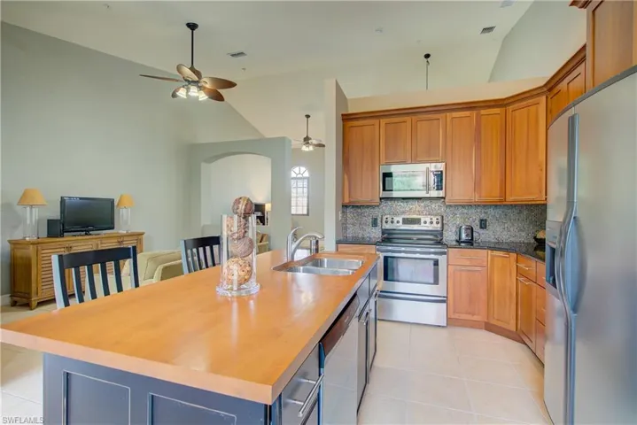 Kitchen with a kitchen island with sink, sink, light tile patterned floors, and stainless steel appliances