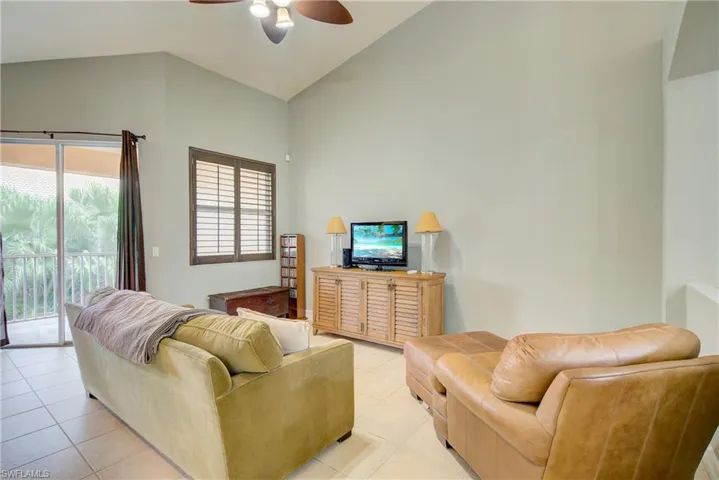 Tiled living room featuring high vaulted ceiling and ceiling fan