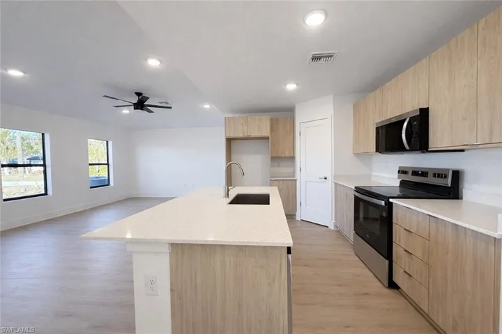 Kitchen featuring appliances with stainless steel finishes, modern cabinets, light brown cabinetry, light stone countertops, and recessed lighting