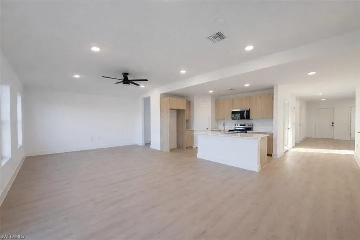 Kitchen featuring open floor plan, a center island with sink, light wood finished floors, appliances with stainless steel finishes, and recessed lighting