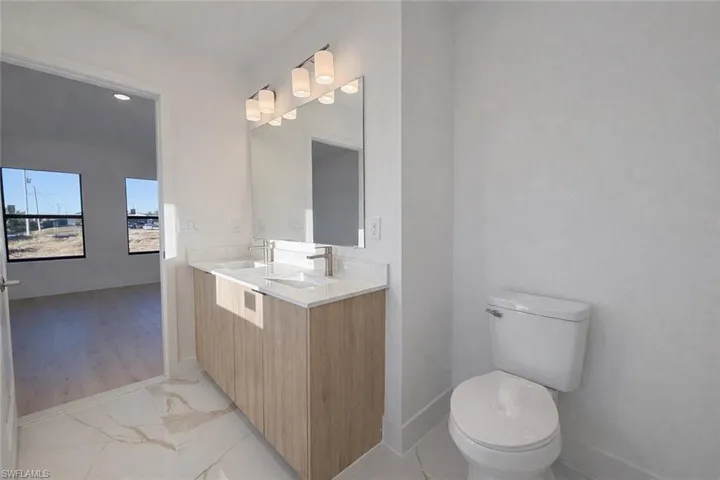 Bathroom featuring double vanity and light marble finish floors