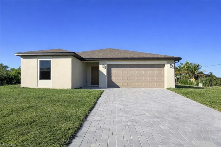 View of front of home featuring a front yard, stucco siding, decorative driveway, and an attached garage