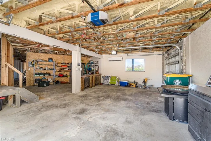 Expansive garage featuring a concrete floor, exposed wood beam ceiling, and a prominent garage door mechanism